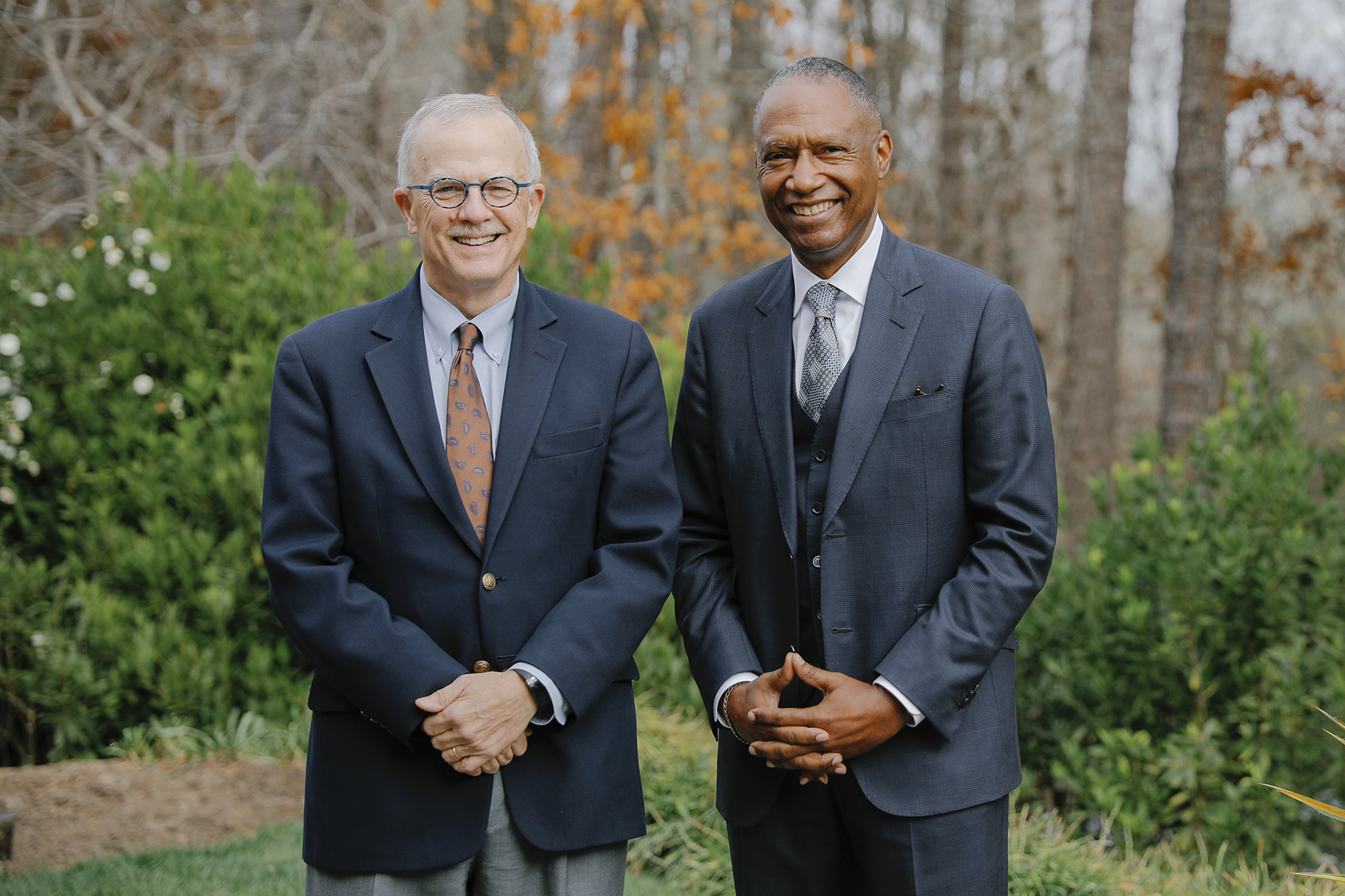 Dean Mike Smith stands beside LGFCU CEO Maurice Smith outside among green trees and bushes on the UNC-Chapel Hill campus.