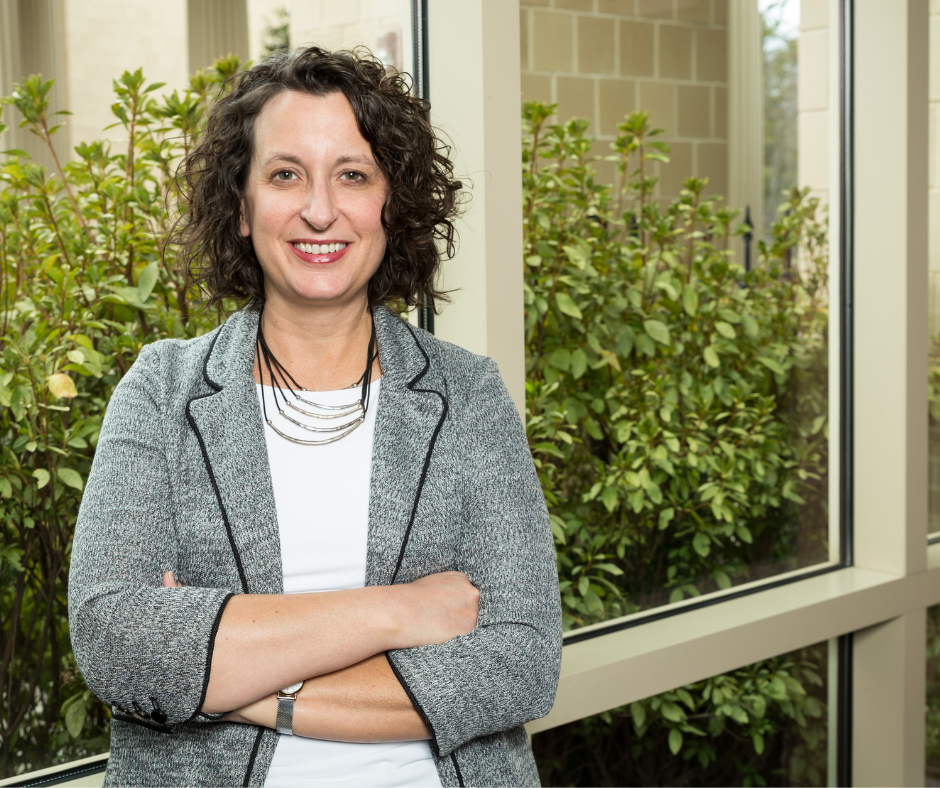 Aimee Wall stands in front of a window in the School of Government.