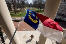The North Carolina state flag flies over the steps to South Building on the UNC campus.