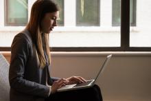 A young woman types on her laptop