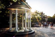 A student drinks from the Old Well at UNC-Chapel Hill while a line of fellow students waits their turns. 